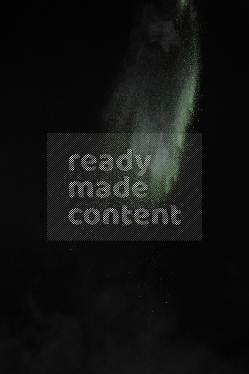 A side view of green powder explosion on black background