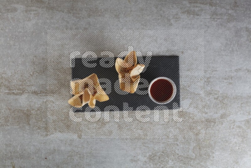 wonton cups with soy sauce ramkin on rectangle slate on grey textured counter top