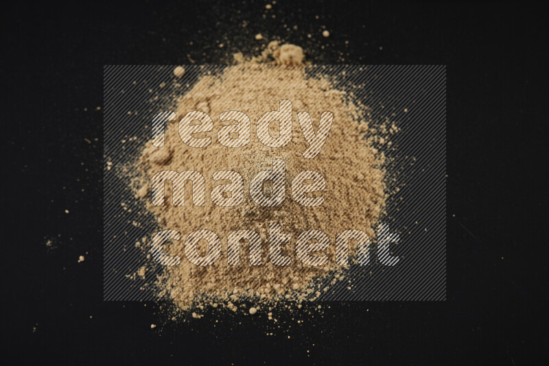 A bunch of ground ginger powder on black background