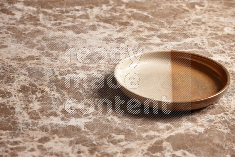 A multicolored pottery oven plate on beige marble background