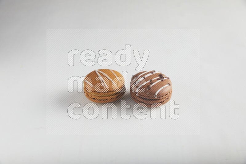 45º Shot of of two assorted Brown Irish Cream, and Brown white Chocolate Caramel macarons on white background