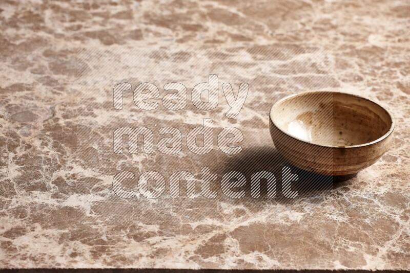 A beige pottery bowl on beige marble background