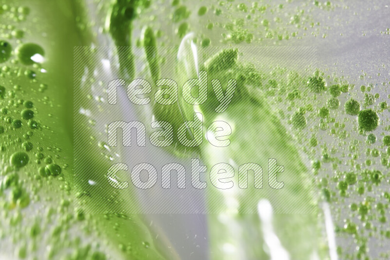 لقطات مقربة لقطرات ألوان مائية خضراء على سطح الزيت على خلفية بيضاء