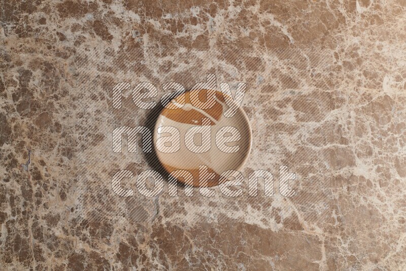 A multicolored pottery plate on beige marble background