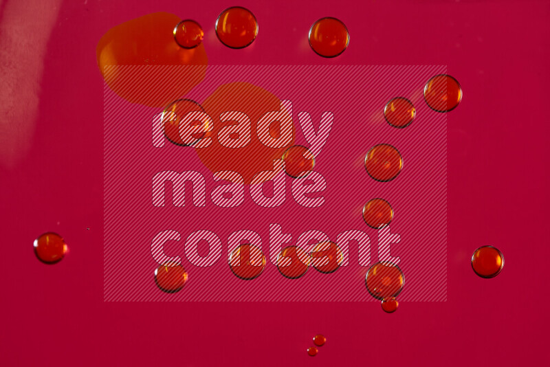 Close-ups of abstract yellow watercolor drops on oil Surface on red background