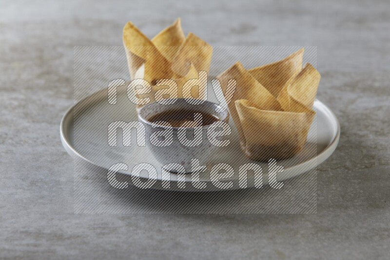 wonton cups with soy sauce ramkin on grey ceramic plate on grey textured counter top