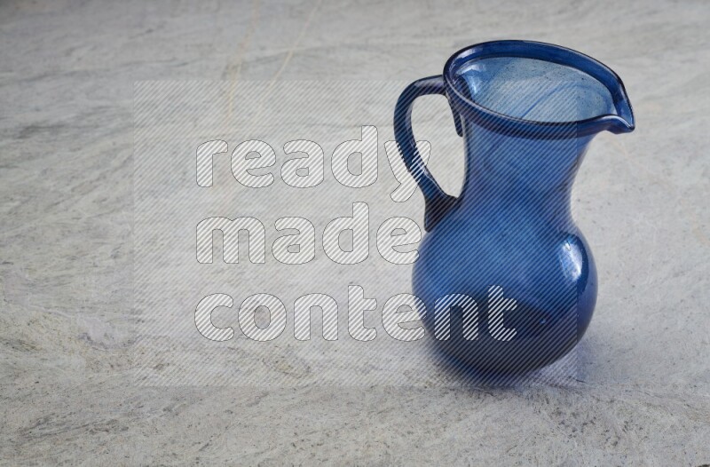 A colored glass jug on grey marble background