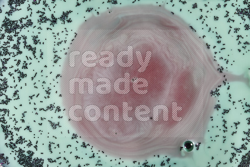 A close-up of swirls of red with sparkling purple glitter scattered on green background