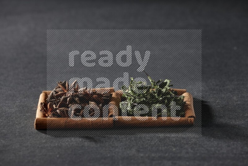 مربعان من أعواد القرفة ممتلئان باليانسون النجمي والنعناع المجفف علي خلفية سوداء