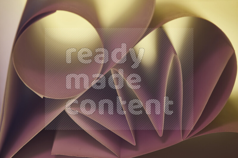 An artistic display of paper folds creating a harmonious blend of geometric shapes, highlighted by soft lighting in pink and warm tones