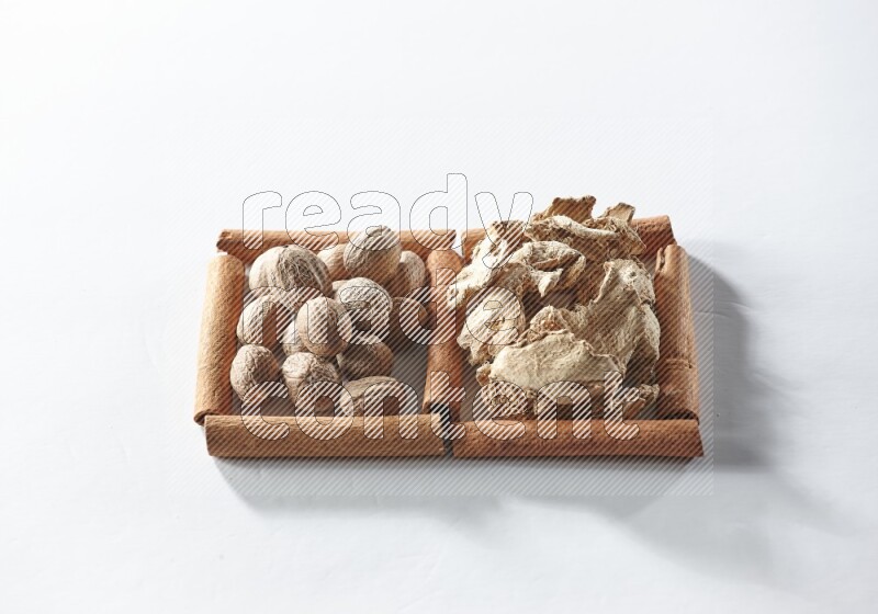 مربعان من أعواد القرفة ممتلئان بالزنجبيل المجفف وجوزة الطيب علي خلفية بيضاء