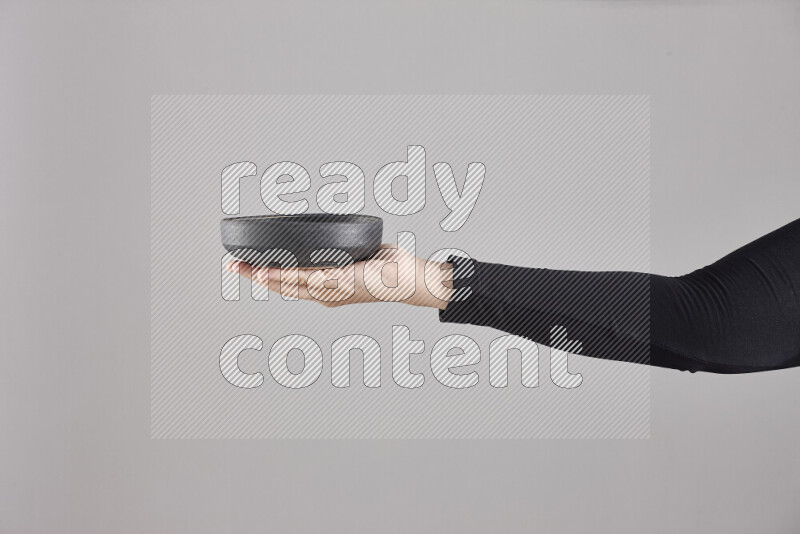 A woman in black abaya holding different pottery essentials in different positions