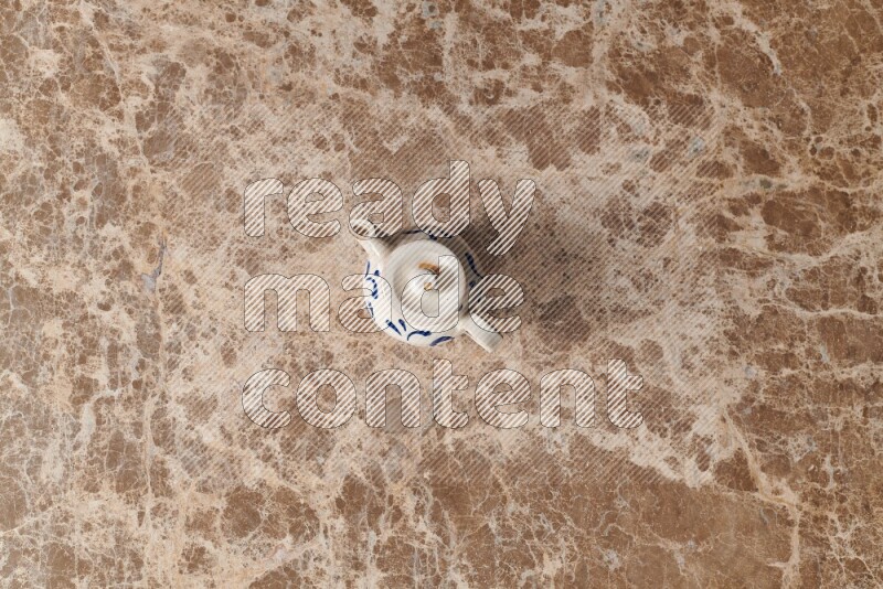 A pottery teapot on beige marble background