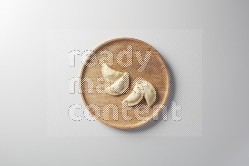Four Sambosas on a wooden round plate on a white background