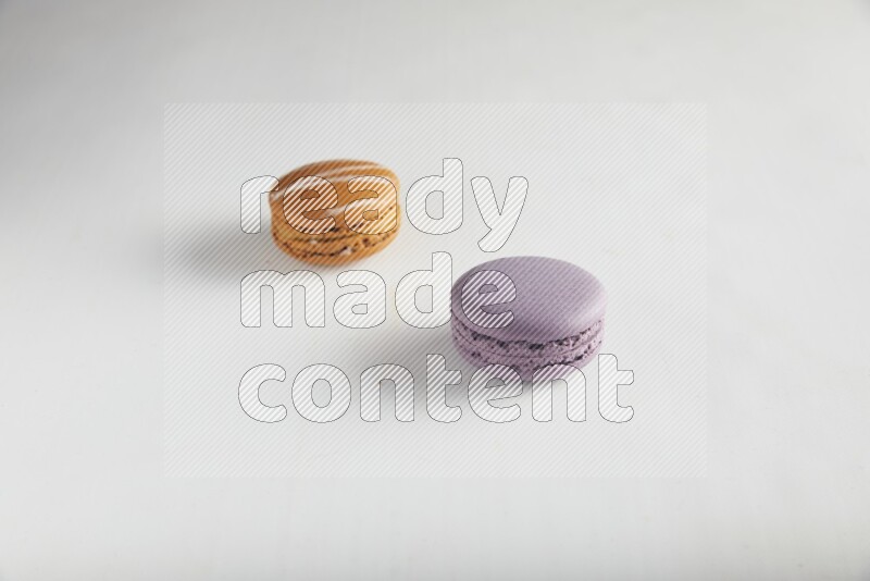 45º Shot of of two assorted Brown Irish Cream, and Purple Blueberry macarons on white background