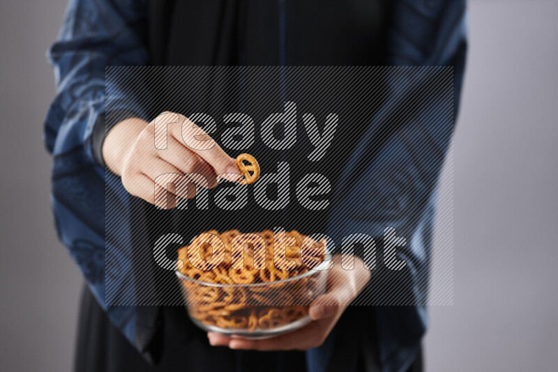 Woman in abaya holding different kinds of snacks in different positions
