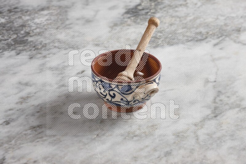 Decorative pottery pot with wooden honey dipper in it on grey marble background