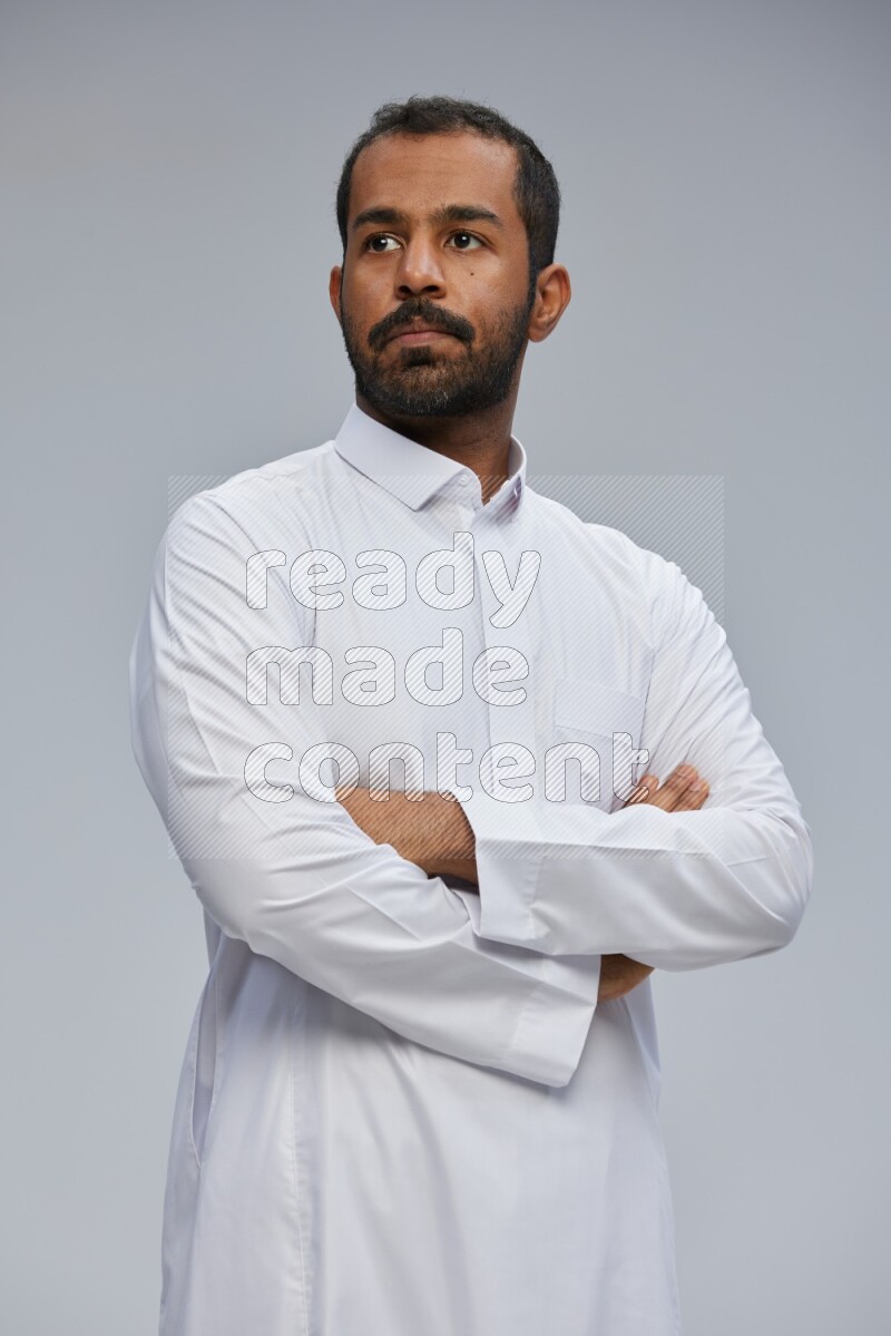 Saudi man wearing Thob standing with crossed arms on Gray background