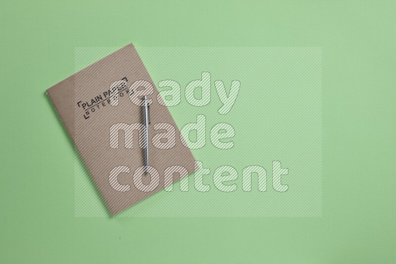 A notebook with different school supplies on green background