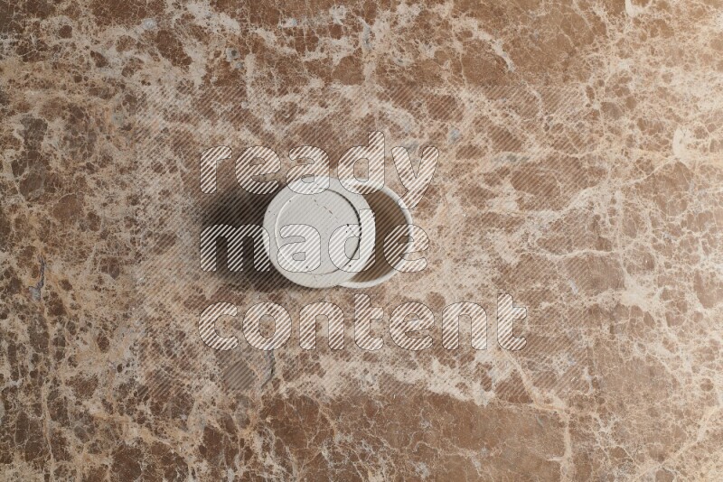 A pottery cup on beige marble background