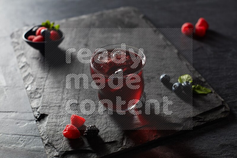 A glass of mixed berries juice on black background