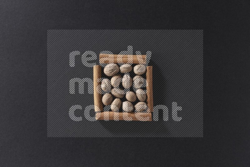 A single square of cinnamon sticks full of nutmeg on black flooring