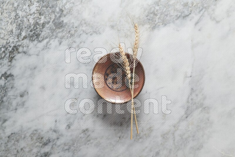 Wheat stalks on decorative pottery plate on grey marble background