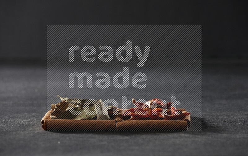 مربعان من أعواد القرفة ممتلئان بالفلفل الحار المجفف وأوراق الغار علي خلفية سوداء