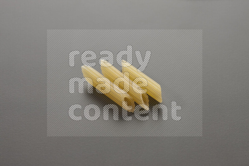 Mini penne pasta on grey background