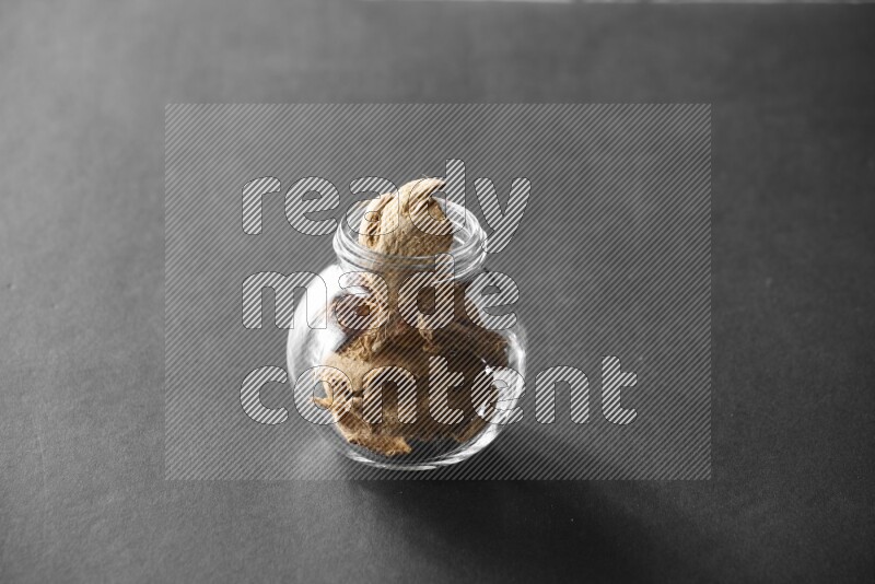 A glass spice jar full of ginger on black flooring