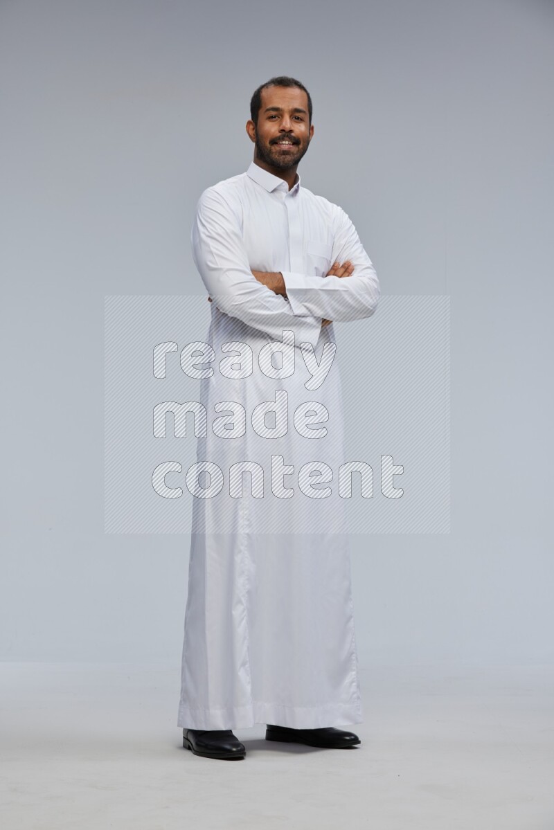 Saudi man wearing Thob standing with crossed arms on Gray background