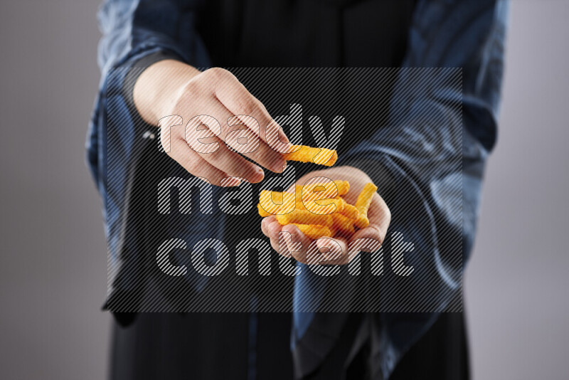 Woman in abaya holding different kinds of snacks in different positions