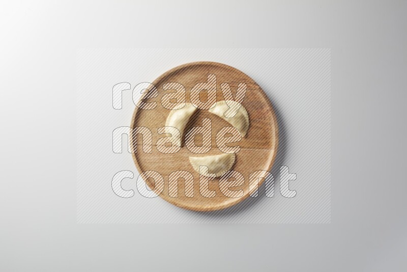 Three Sambosas on a wooden round plate on a white background