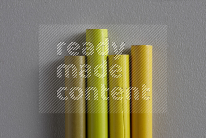 A collection of sharpened colored pencils arranged showcasing a gradient of yellow hues on grey background
