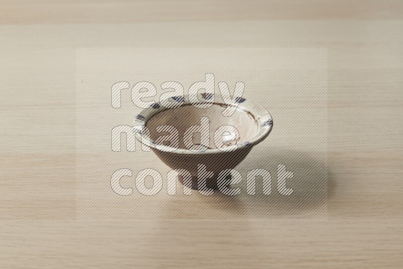 A decorative pottery bowl on light wooden background