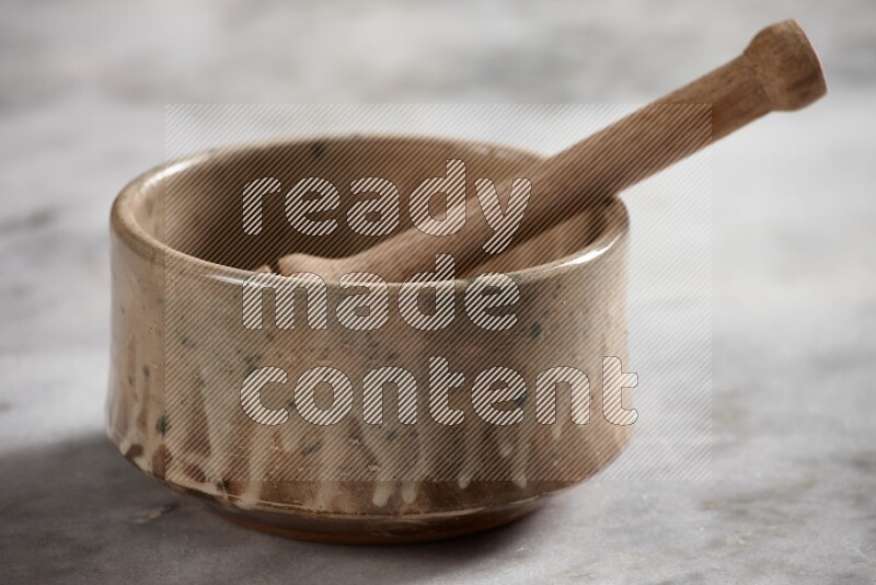 Multicolored pottery bowl with wooden honey dipper in it on grey marble background