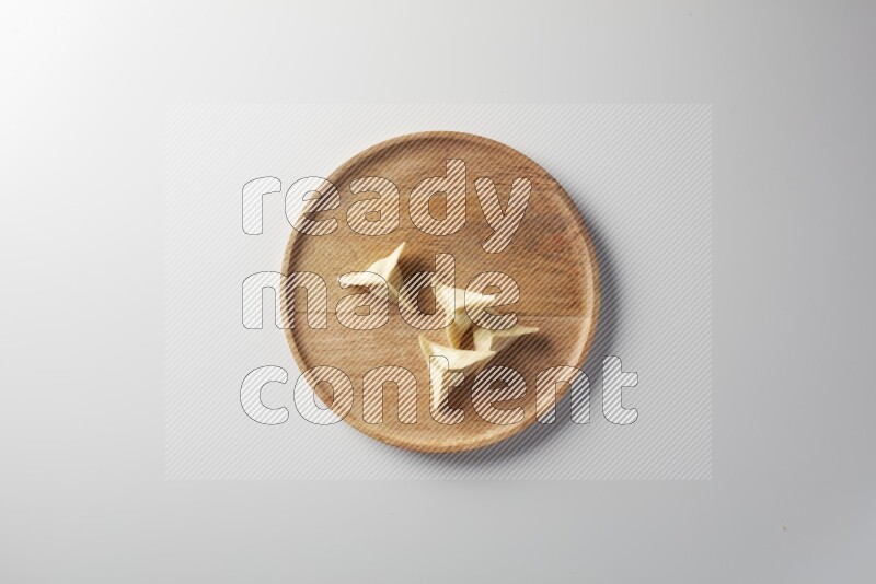 Four Sambosas on a wooden round plate on a white background