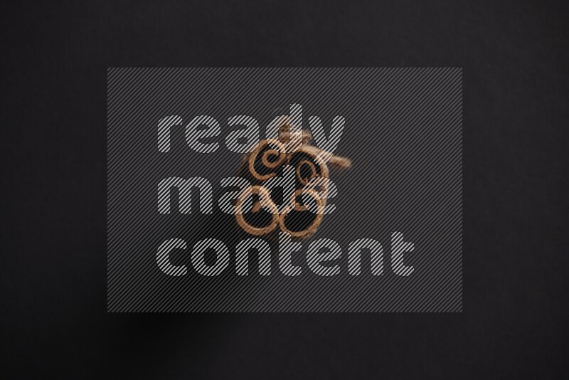 4 أعواد من القرفة مربوطة علي خلفية سوداء