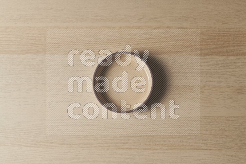 A beige pottery oven bowl on light wooden background