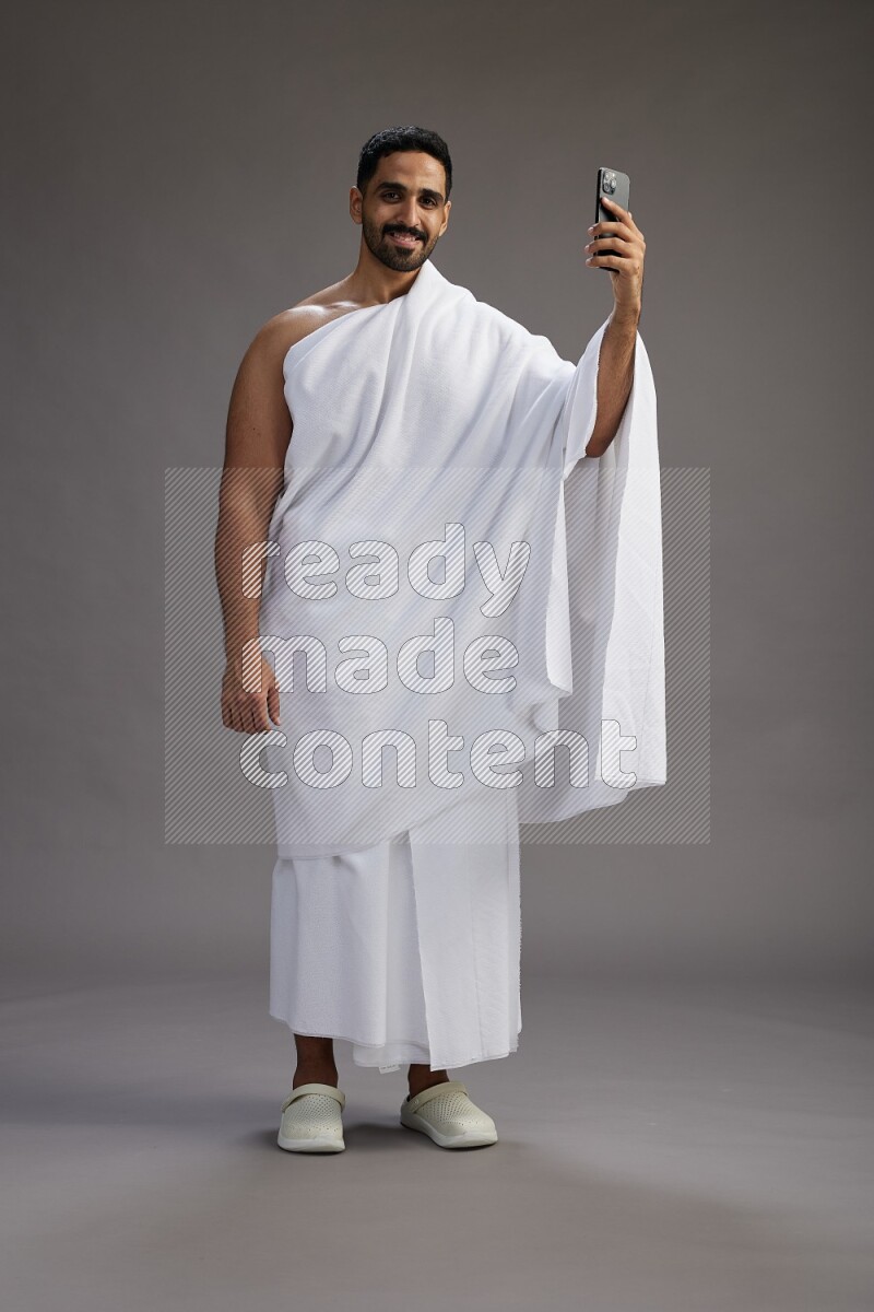 A man wearing Ehram Standing taking selfie on gray background