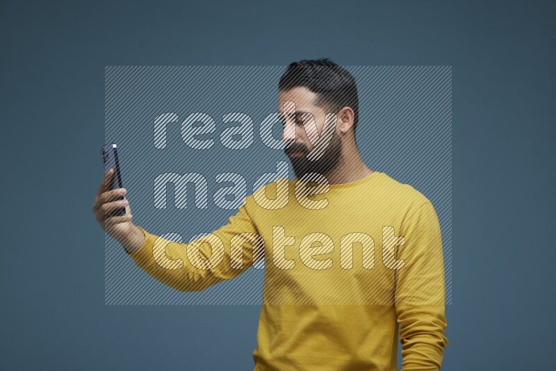 Man Taking a Selfie  in a blue background wearing a yellow shirt