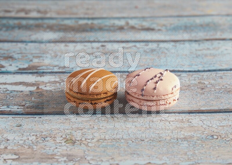 45º Shot of of two assorted Brown Irish Cream, and pink orange blossom  macarons on light blue background