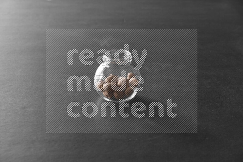 جوزة الطيب في وعاء زجاجي علي خلفية سوداء