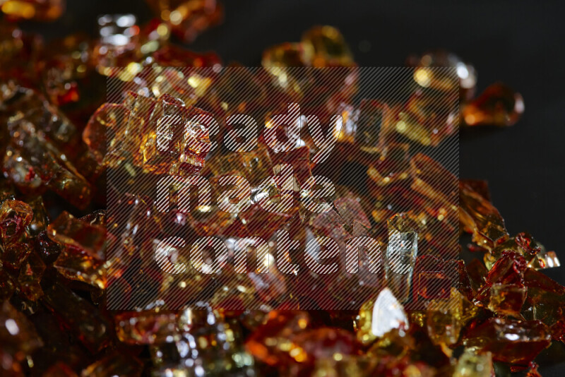 Transparent orange fragments of glass scattered on a black background