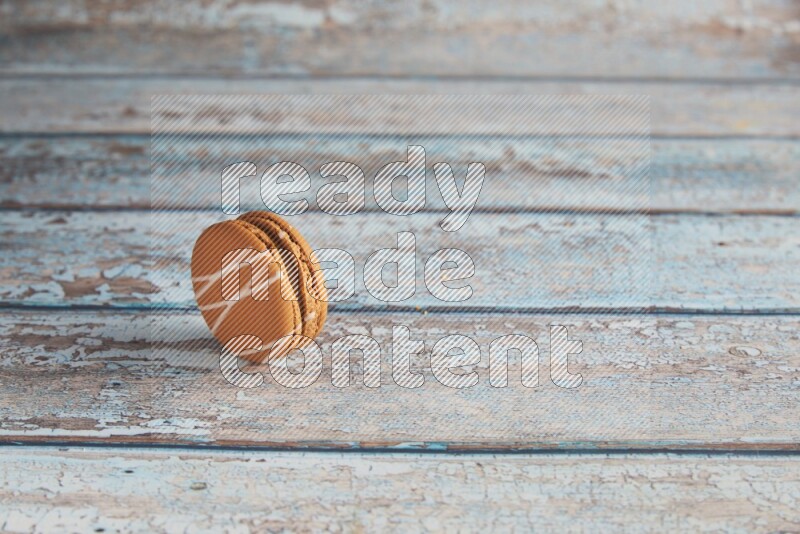 45º Shot of Brown Irish Cream macaron on light blue wooden background