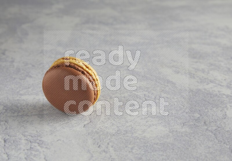 45º Shot of Yellow and Brown Chai Latte macaron on white  marble background