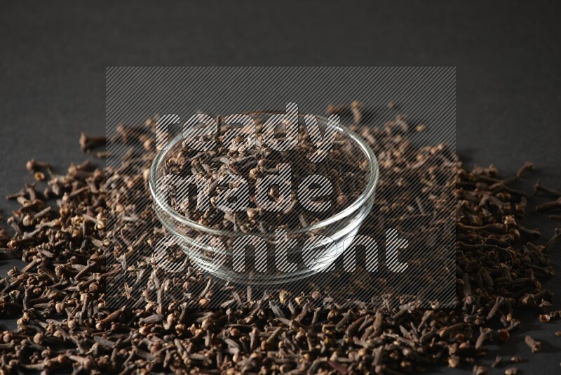 A glass bowl full of cloves on a black flooring