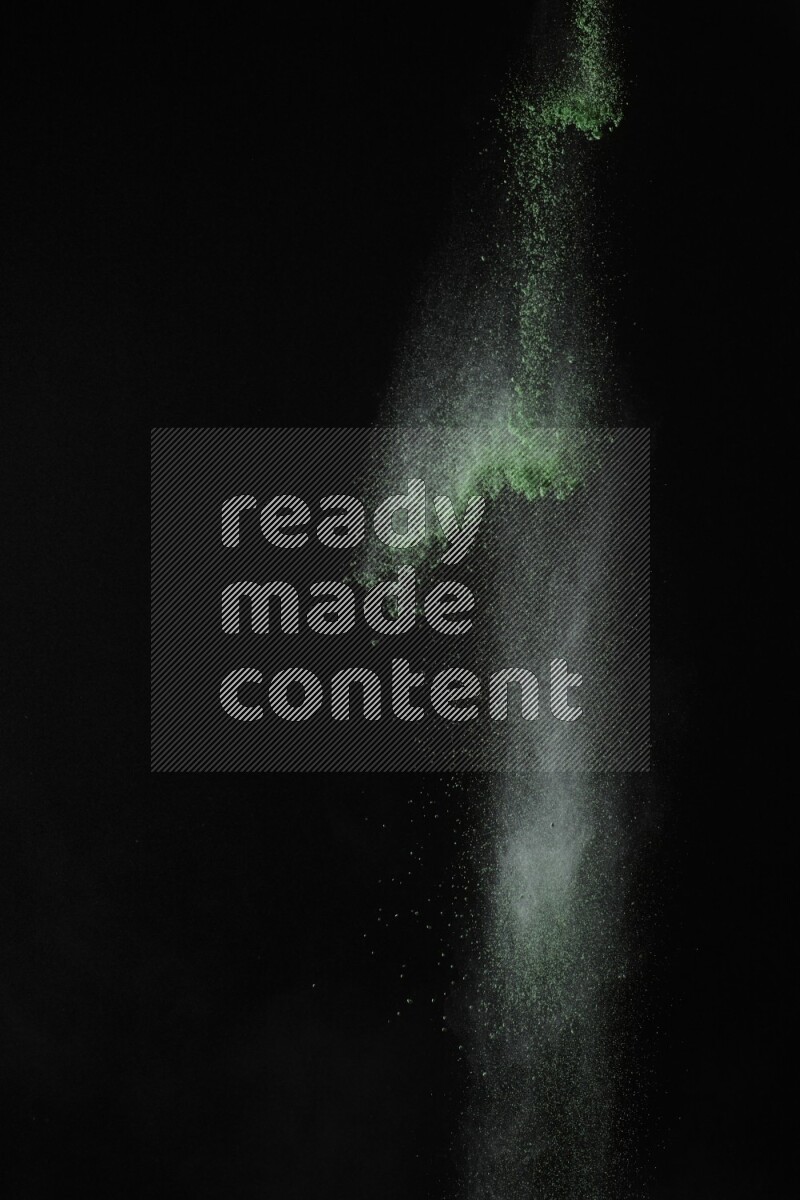 A side view of green powder explosion on black background