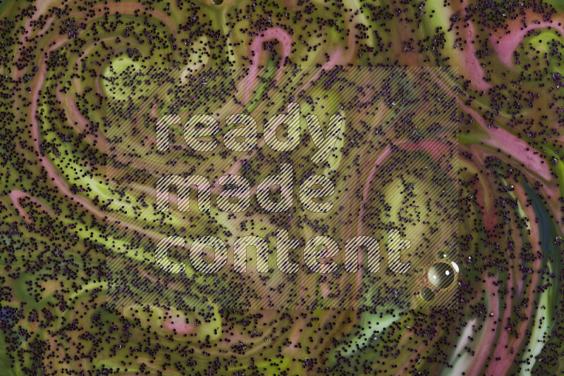 A close-up of sparkling purple glitter scattered on swirling green and red background