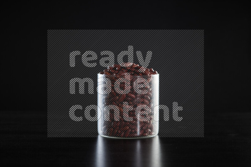 Red kidney beans in a glass jar on black background
